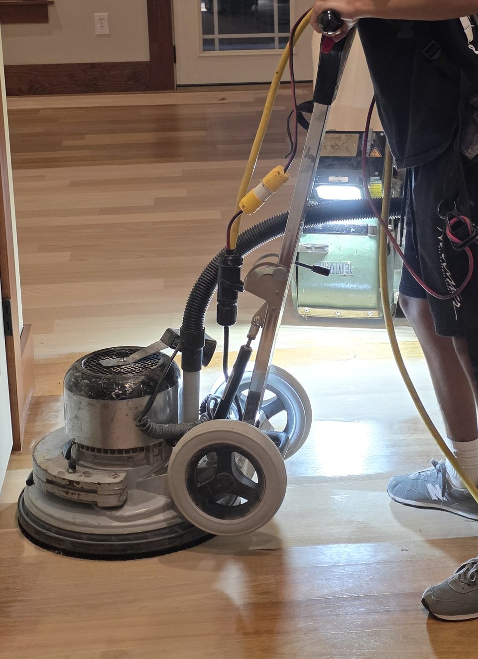 Craftsman operating a sanding machine on a wood floor