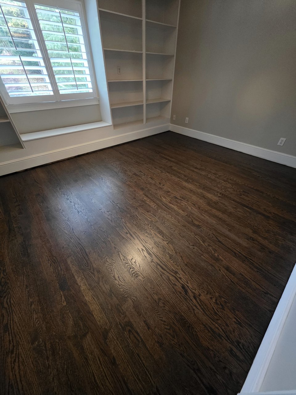 Dark wood floor beside shuttered windows
