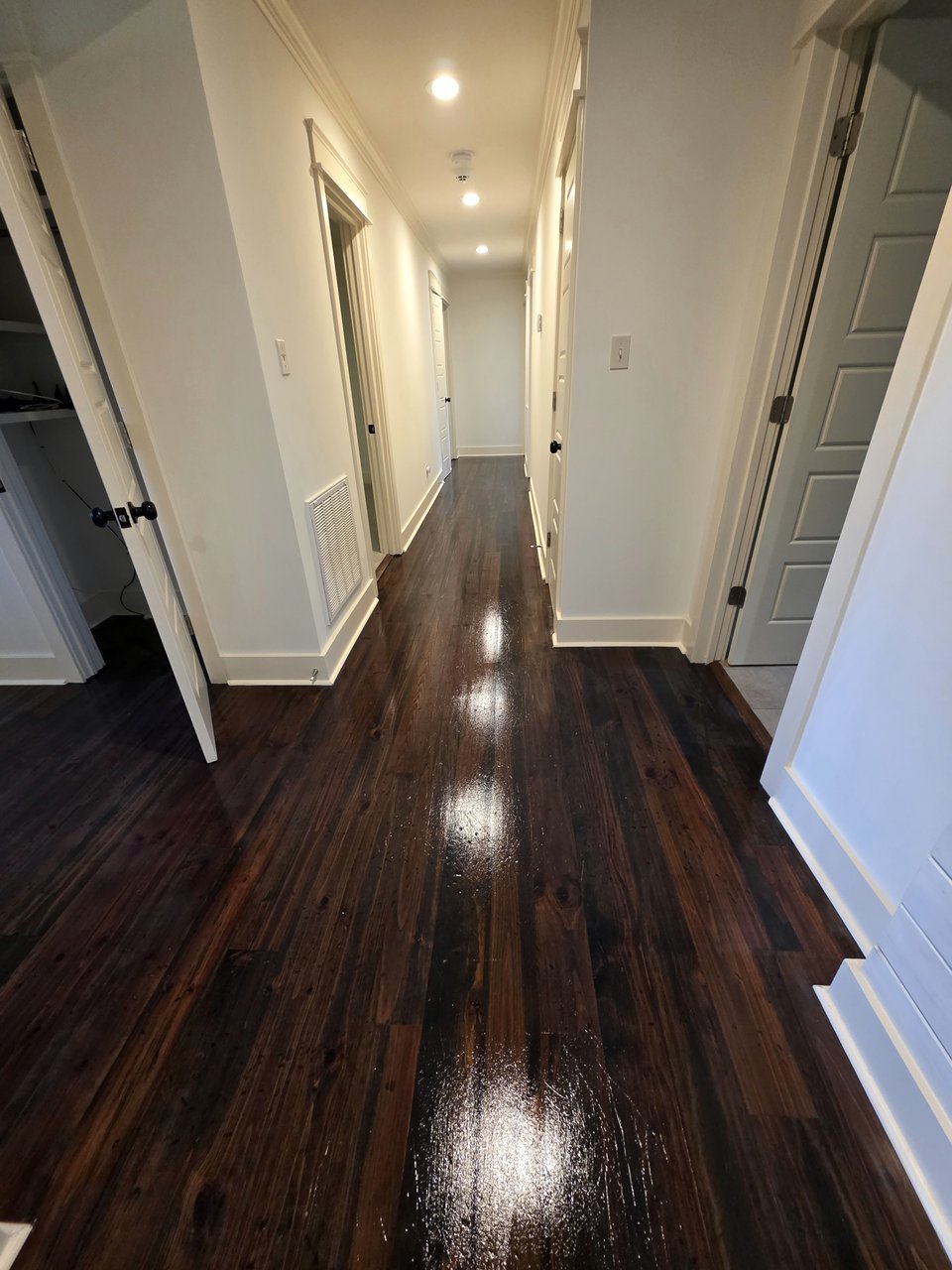 Glossy dark floor along a white hallway