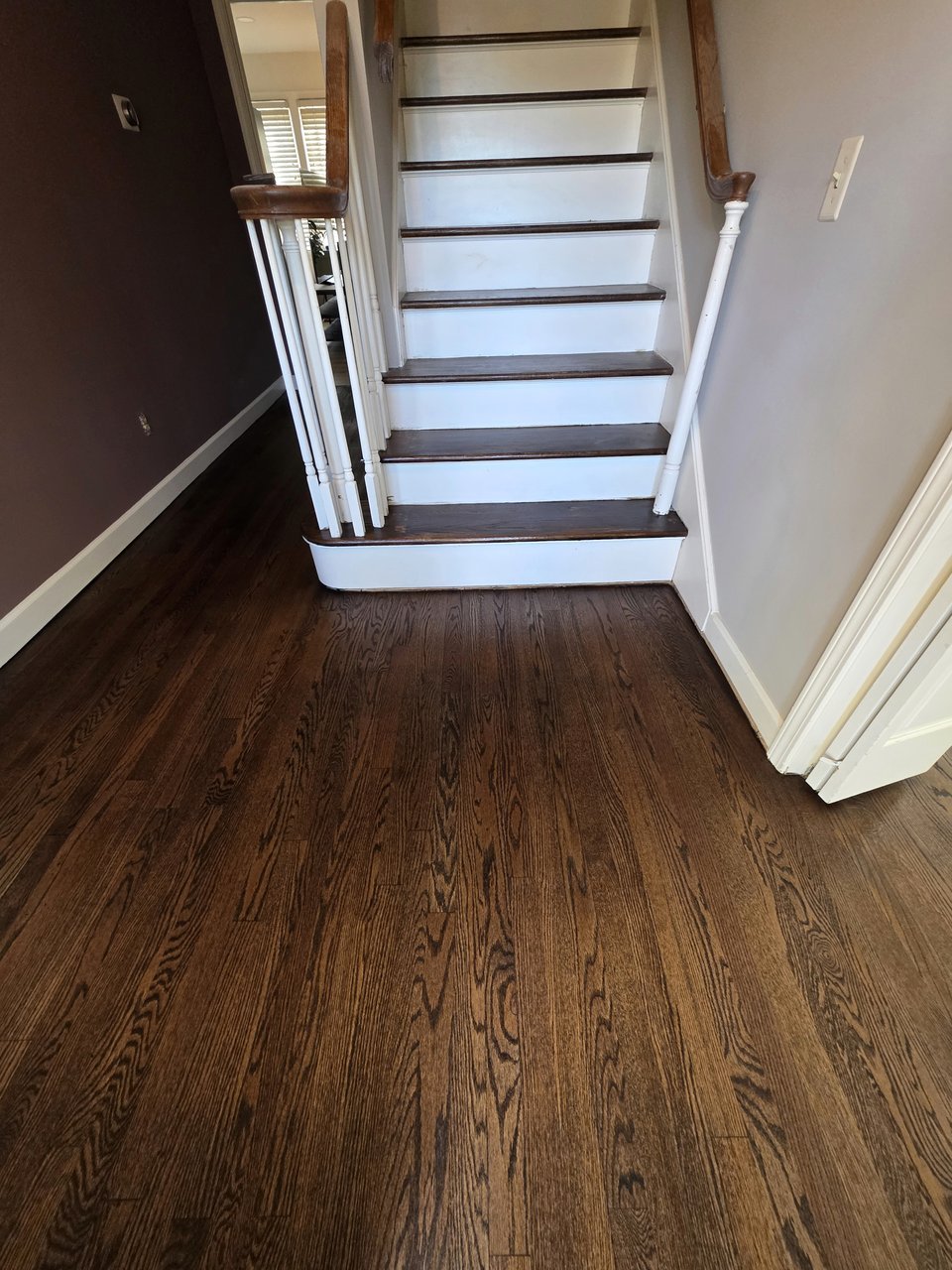 Wood flooring at the foot of a straight staircase